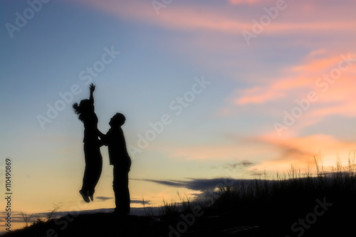 Young couple silhouette jumping sunset happy time