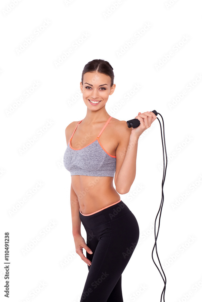 Skipping rope is her way to fitness. Portrait of an attractive young sporty woman holding a skipping rope while standing over white isolated background.