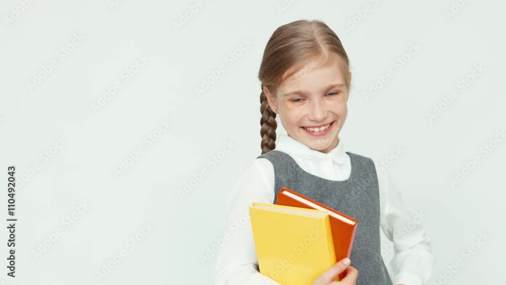 Portrait cute schoolgirl 7-8 years holding books on white background and smiling with teeth at camera Portrait cute schoolgirl 7-8 years holding books on white background and smiling with teeth at camera