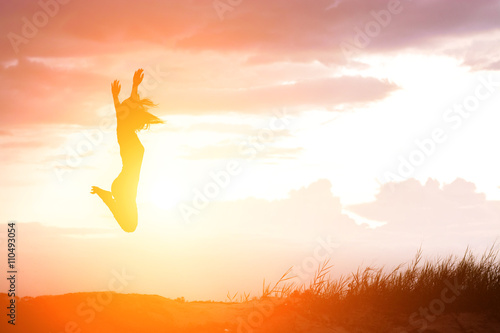 Happy woman jumping against beautiful sunset