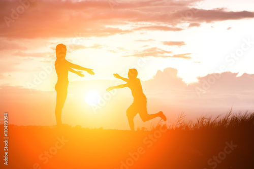 Mother encouraged her son outdoors at sunset  silhouette concept