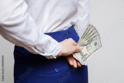 Unrecognizable businesswoman hiding dollars behind back