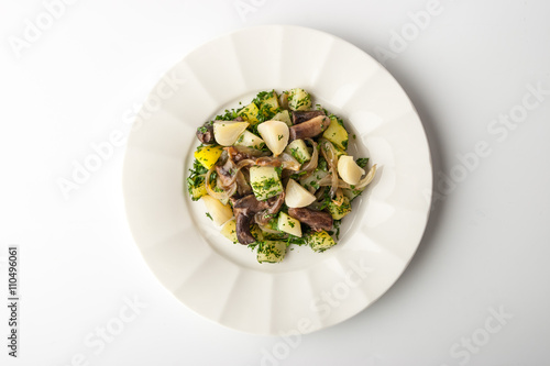Salad with mushrooms on a relief plate on a white background