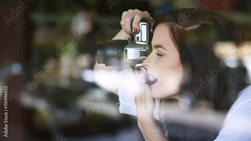 Pretty young traveller girl taking photos out of cafe window