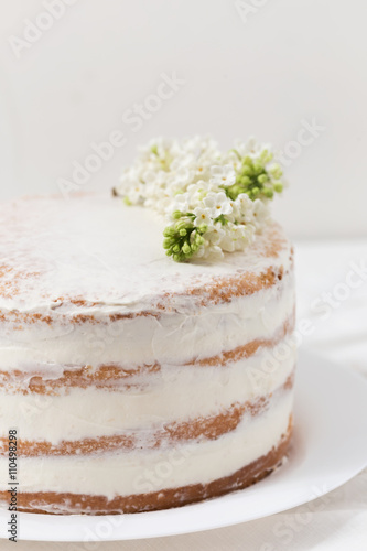 Rustic wedding cake with white lilac, light background, close up, selective focus