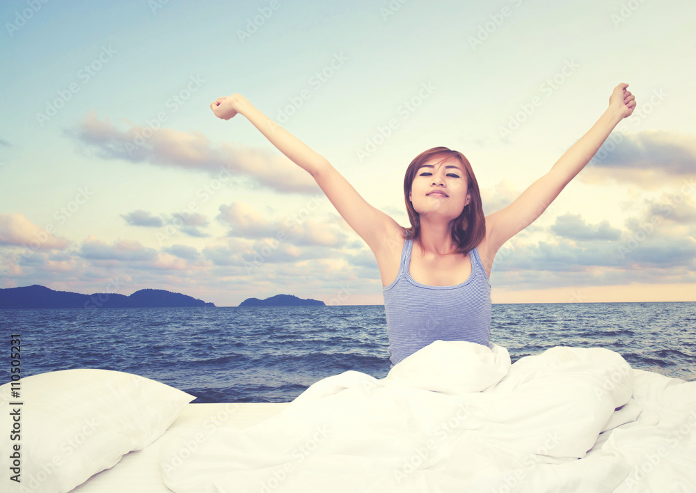Tired sleepy woman waking up and yawning with a stretch while si Tired sleepy woman waking up and yawning with a stretch while si