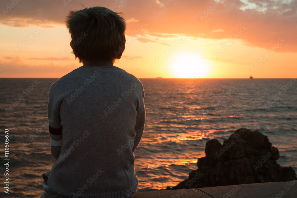 Silhouette of a Child in Front of Sea at Sunset