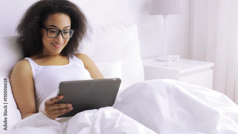 african woman with tablet pc in bed at home african woman with tablet pc in bed at home