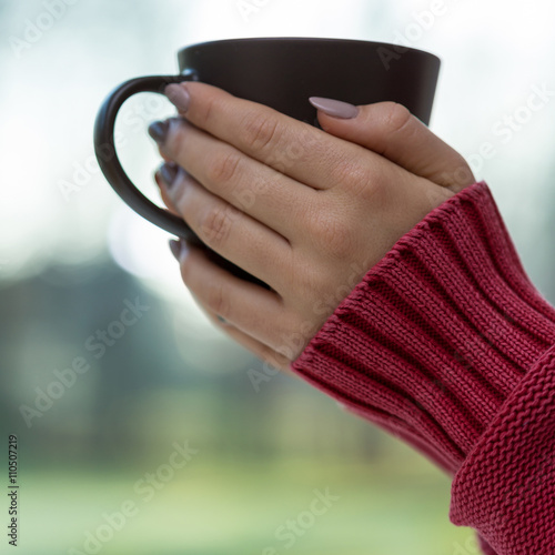 Woman in red sweater holding cup