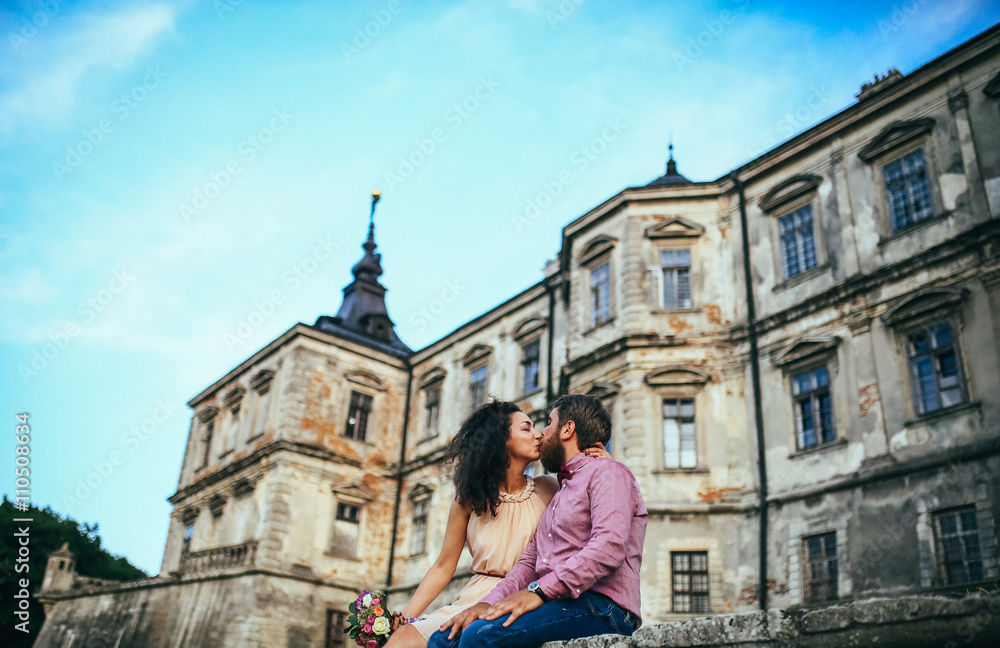 Beautiful couple, posing in near olf castle. Man with beard, woman with curly hair