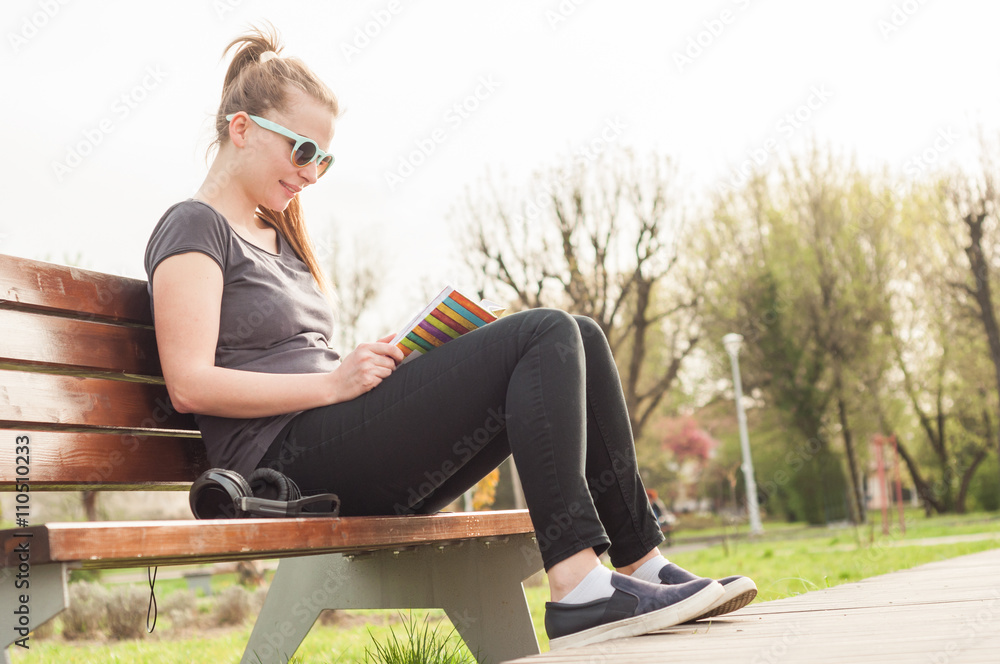 Cute young female sitting on bench and relaxing outside Cute young female sitting on bench and relaxing outside