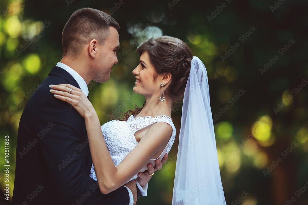 Beautiful young happy wedding couple in park, outdoor, green background. New family.