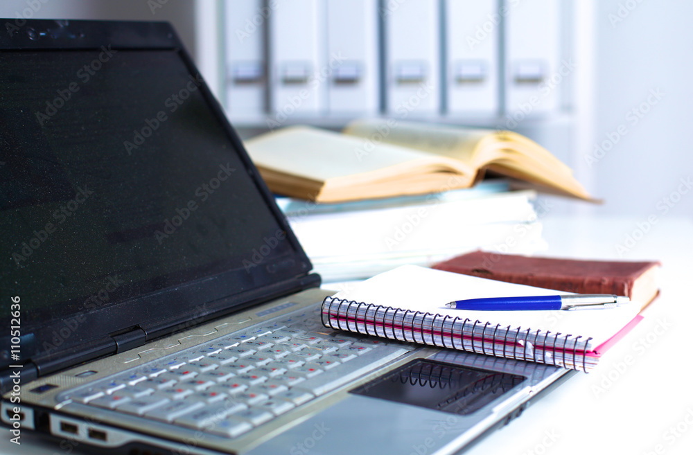 Office table with blank notepad and laptop 