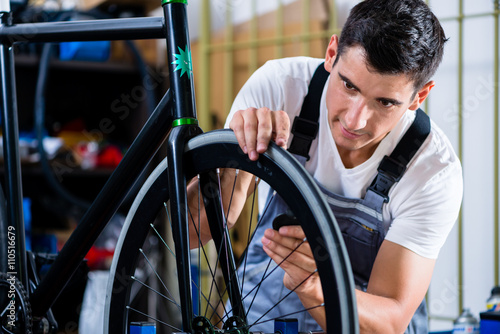 Mechanic repairing bicycle in his workshop © Kzenon