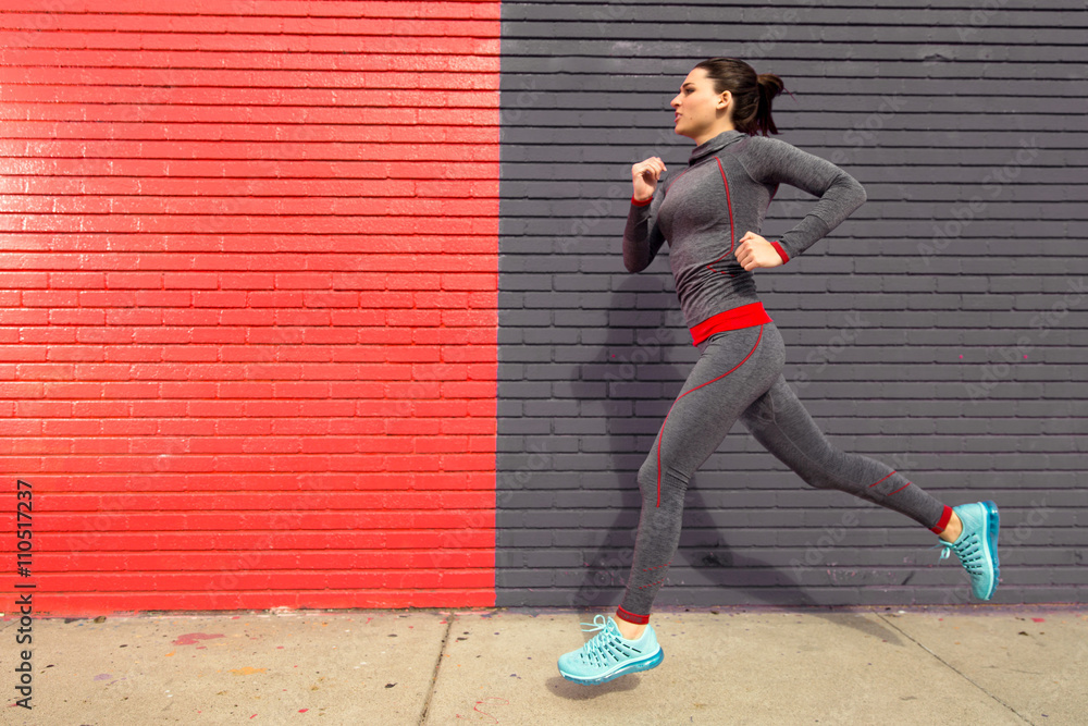 Female runner jogging sprinting in urban setting red gray exercise in motion