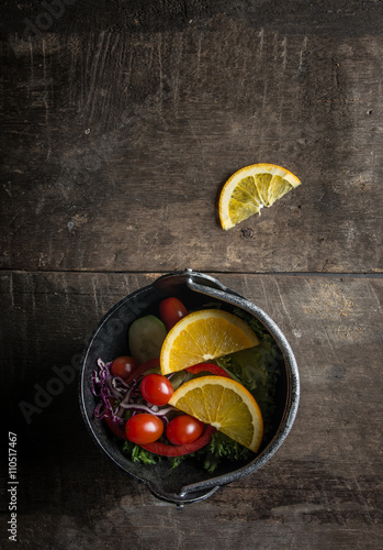 Fresh salad with slice of orange on a wooden background