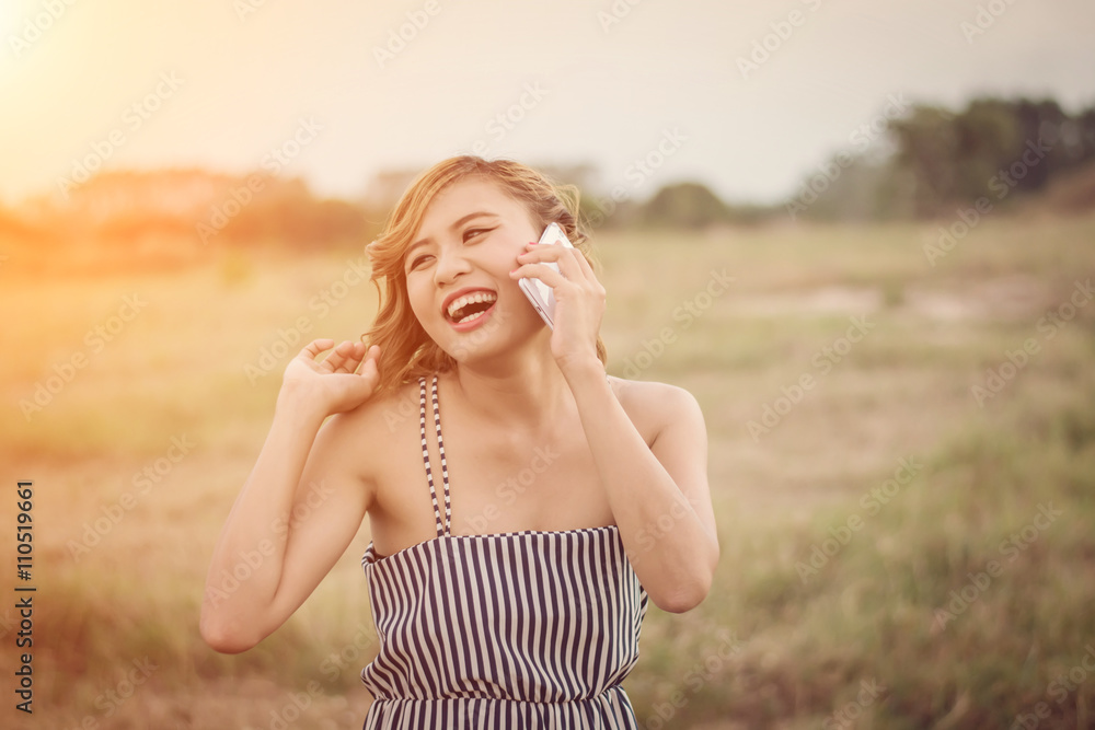 Beautiful sexy woman standing talking on phone in the grass fiel