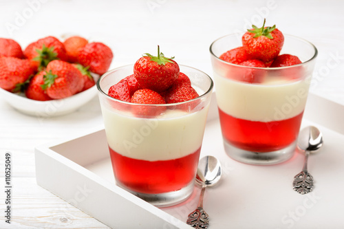 Layered strawberry dessert - panna cotta with strawberry jelly and strawberries.