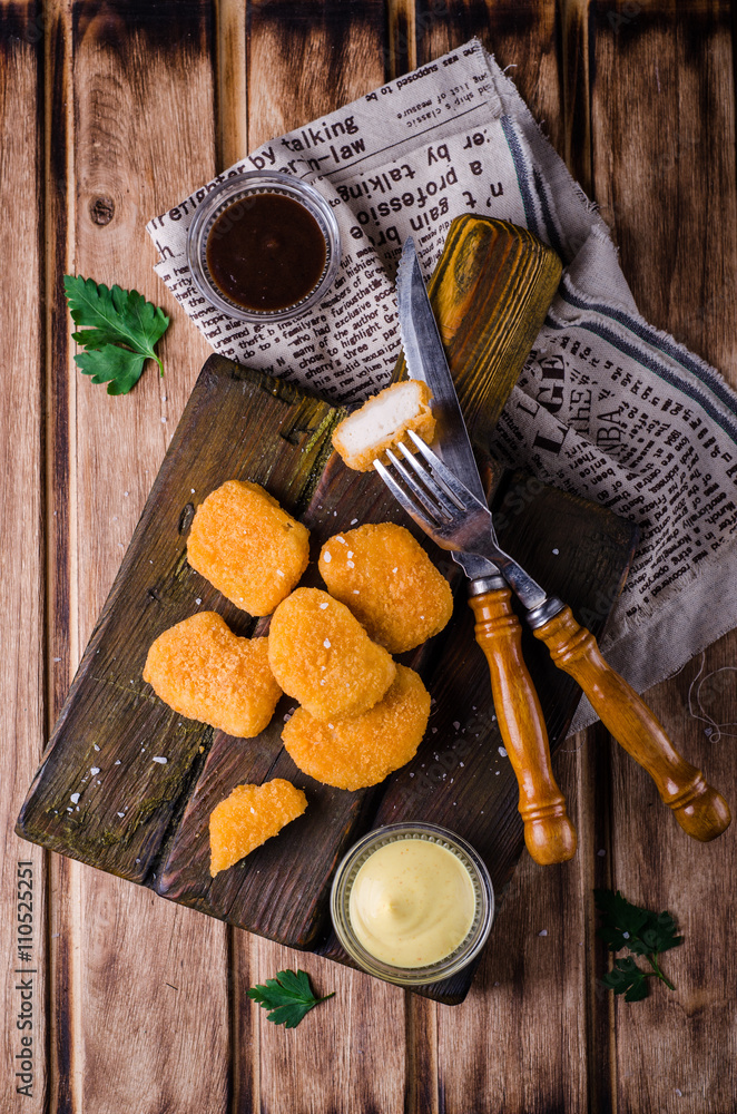 Chicken Nuggets on wooden cutting board with ketchup and sauce, on wooden background. Selective focus. Top view Chicken Nuggets on wooden cutting board with ketchup and sauce, on wooden background. Selective focus. Top view