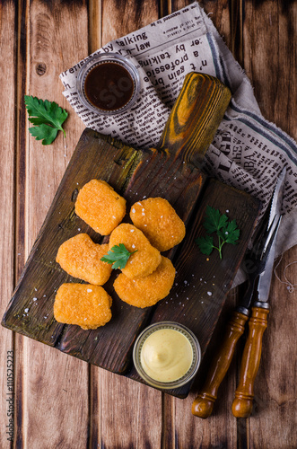 Chicken Nuggets on wooden cutting board with ketchup and sauce, on wooden background. Selective focus. Top view
