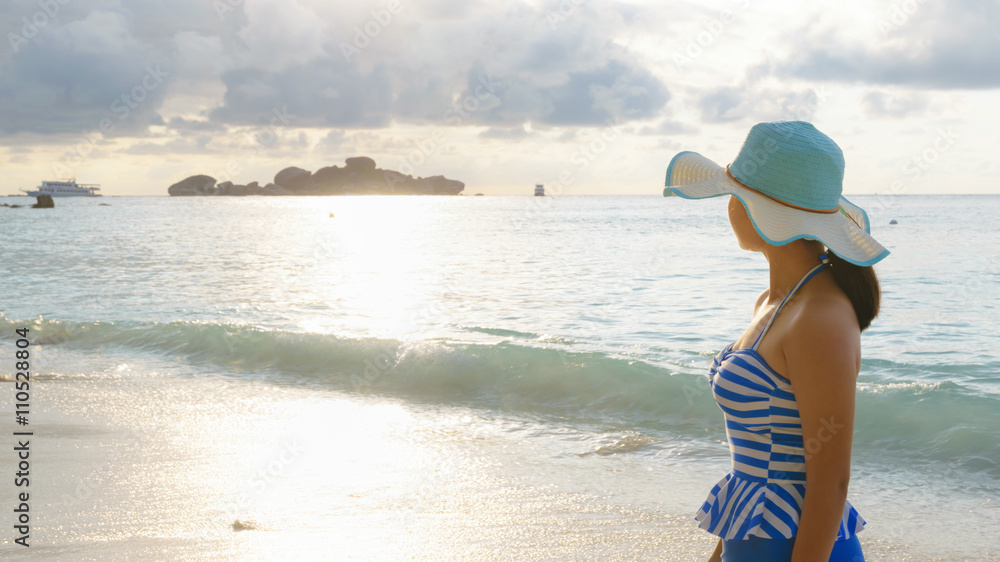 Young girl wearing a hat and swimsuit standing watch nature sky and sea during the sunrise on beach of Honeymoon Bay at Koh Miang, Similan Islands National Park, Phang Nga, Thailand, 19:6 wide screen Young girl wearing a hat and swimsuit standing watch nature sky and sea during the sunrise on beach of Honeymoon Bay at Koh Miang, Similan Islands National Park, Phang Nga, Thailand, 19:6 wide screen