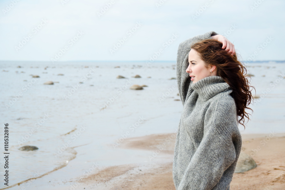 Attractive woman wearing a warm cardigan at the cold beach