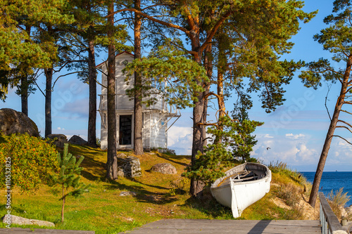 Rocky coast of Baltic sea with white boat photo