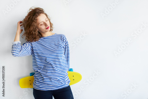  hipster girl holding a skateboard isolated on white