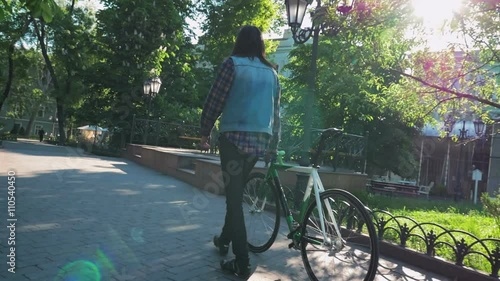 Young hipster man walking with gixed gear bike in the park photo