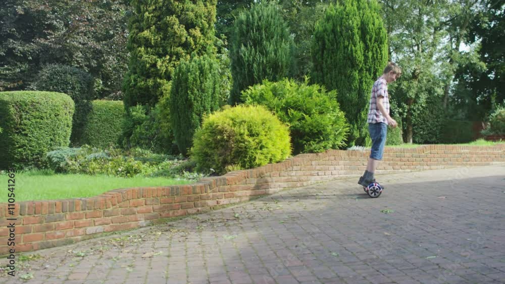 Young boy playing on motorized hover board in the garden Young boy playing on motorized hover board in the garden