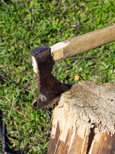 Old ax stuck in a wooden log