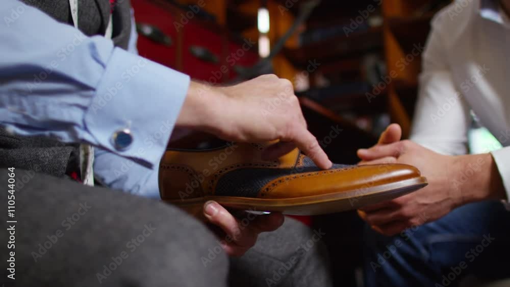  Client in a meeting with tailor, looking at quality of shoe