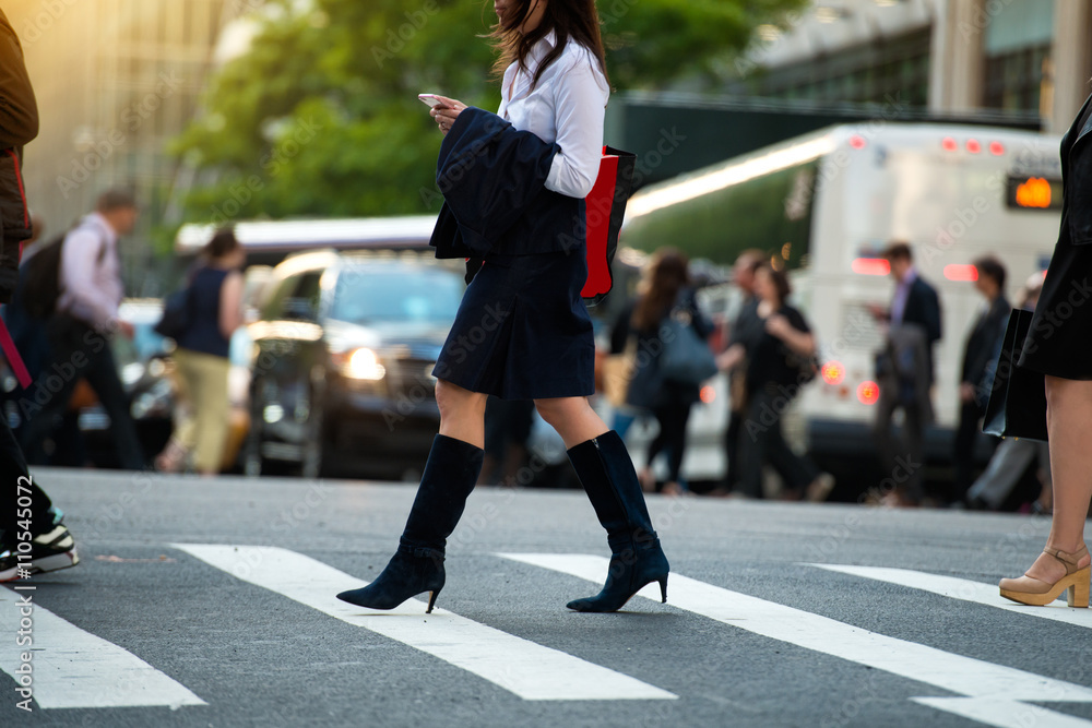 Businesswoman walking on crosswalk and texting on smartphone in city street Businesswoman walking on crosswalk and texting on smartphone in city street
