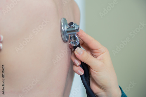 Doctor listening to patients chest with stethoscope in his office at the hospital