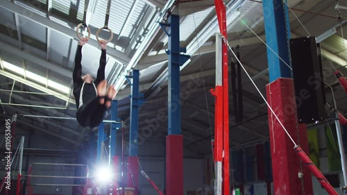  Professional male gymnast training on the rings at the gym. 