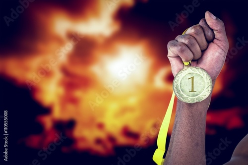 Composite image of athlete holding gold medal after victory