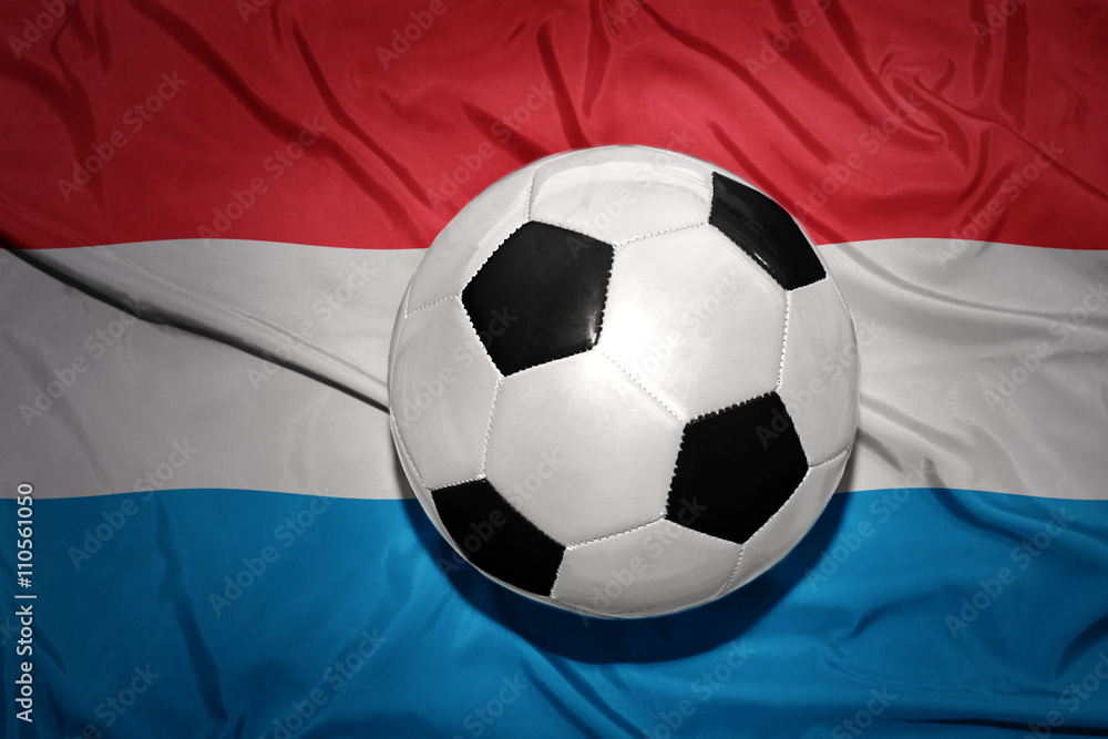Naklejka premium black and white football ball on the national flag of luxembourg