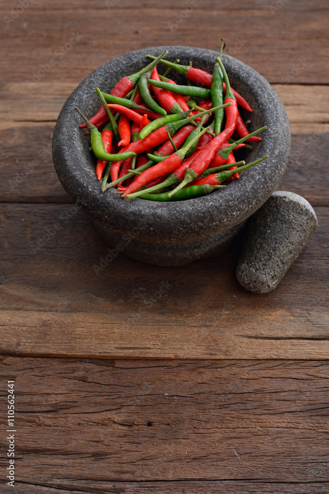 Top view of Chili and stone mortar in wooden tone background Top view of Chili and stone mortar in wooden tone background