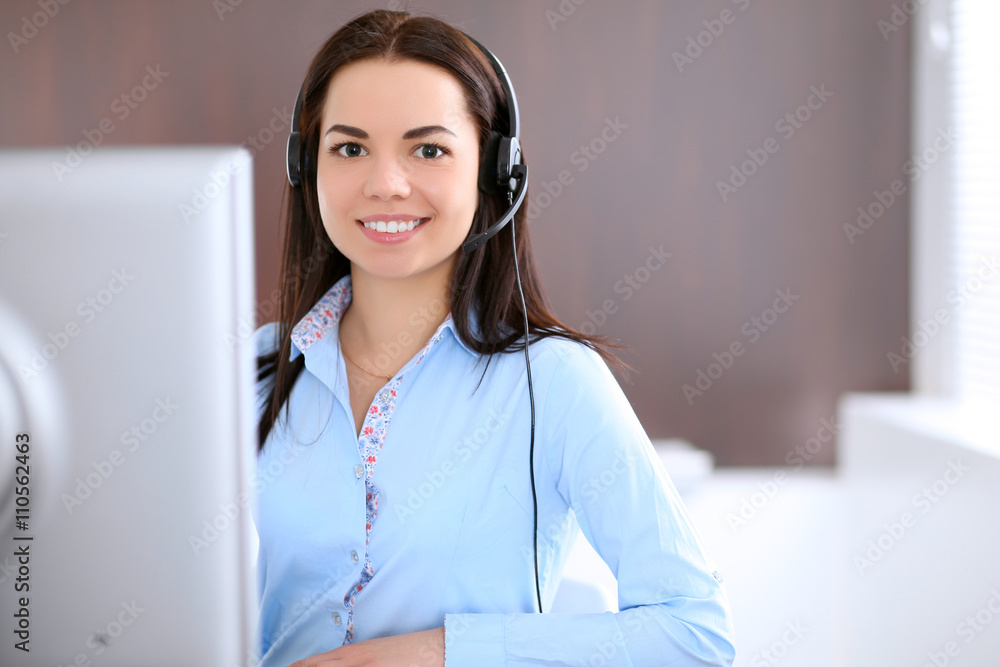 Young business woman in a headset, sitting at the table in the office Young business woman in a headset, sitting at the table in the office
