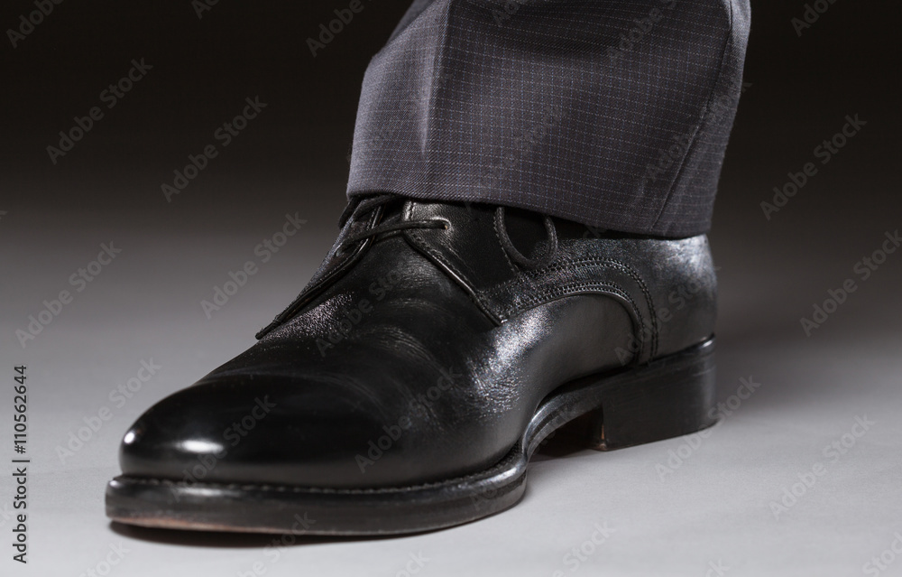 Male leg in black leather shoe