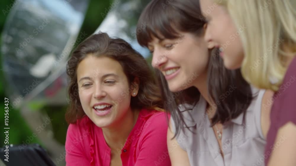 Happy attractive female friends using tablet computer outdoors Happy attractive female friends using tablet computer outdoors