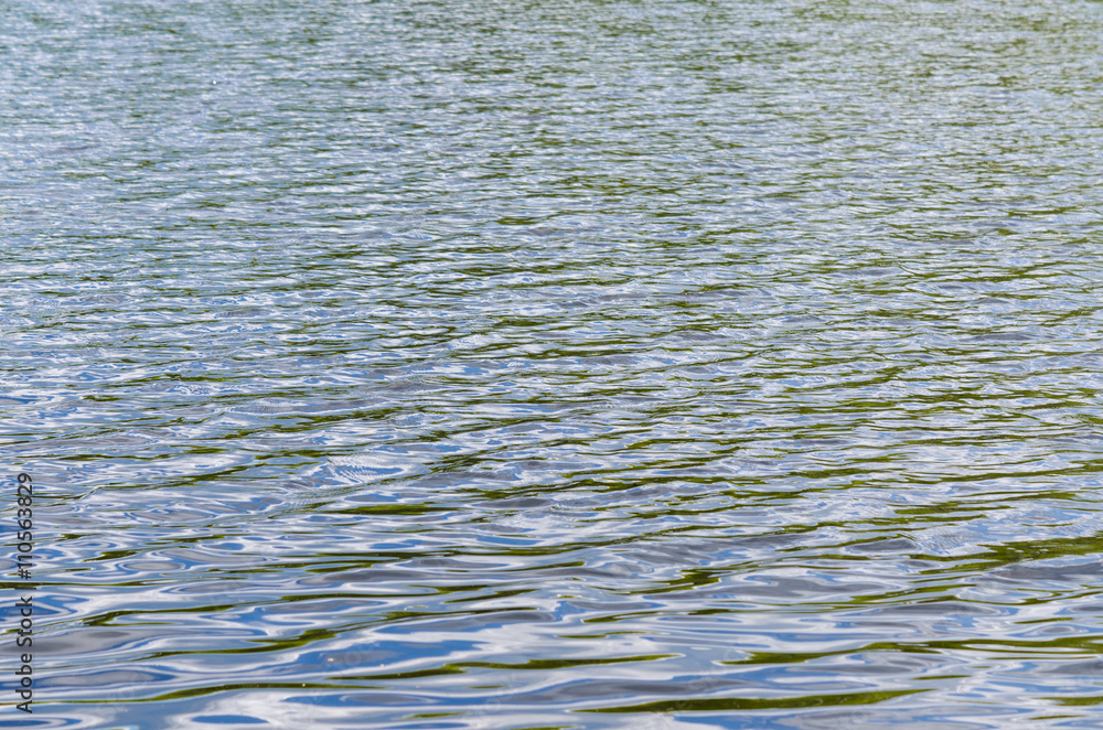 Water surface with ripples and sunrays reflections