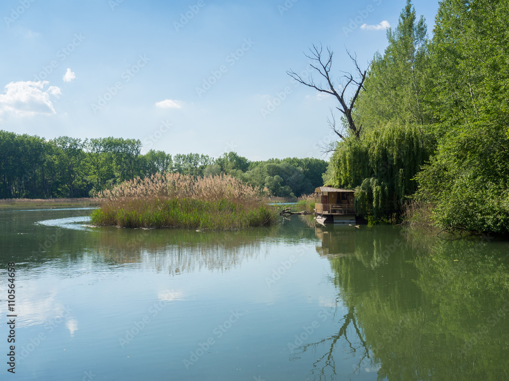 Quiet bank of the Danube river in spring with houseboat and reflections Quiet bank of the Danube river in spring with houseboat and reflections