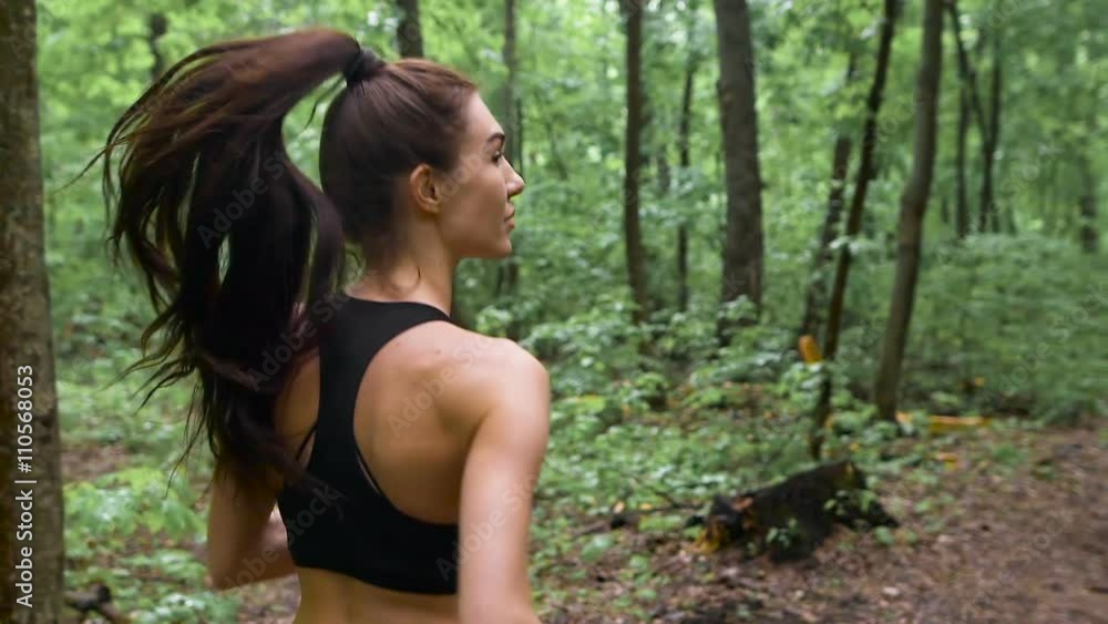Young athletic sporty girl with long hair training in green forest during summer spring season with lots of leaves fallen on forest path. Young athletic sporty girl with long hair training in green forest during summer spring season with lots of leaves fallen on forest path.