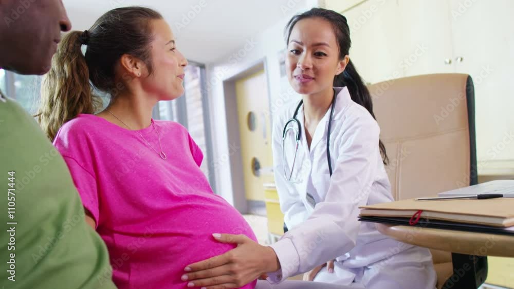 Friendly doctor talking to couple who are expecting a baby Friendly doctor talking to couple who are expecting a baby