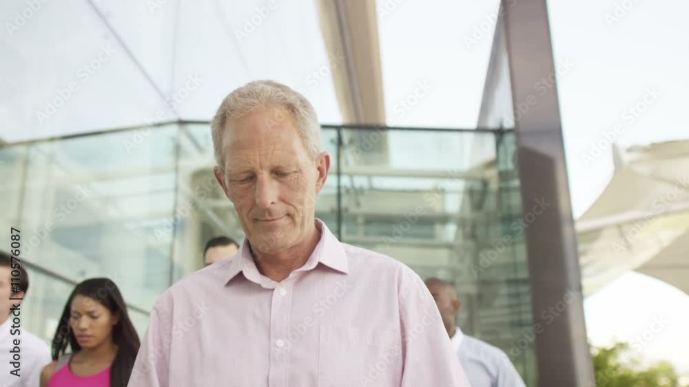 Mixed ethnicity business team walking together outside office building Mixed ethnicity business team walking together outside office building