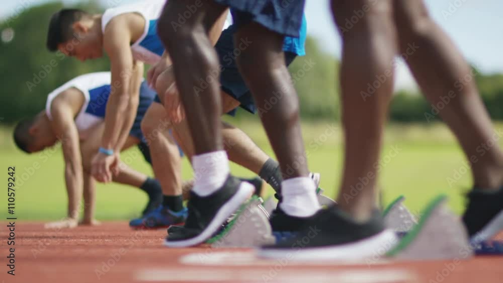 Group of athletes at running track, crouch at starting line before a race Group of athletes at running track, crouch at starting line before a race