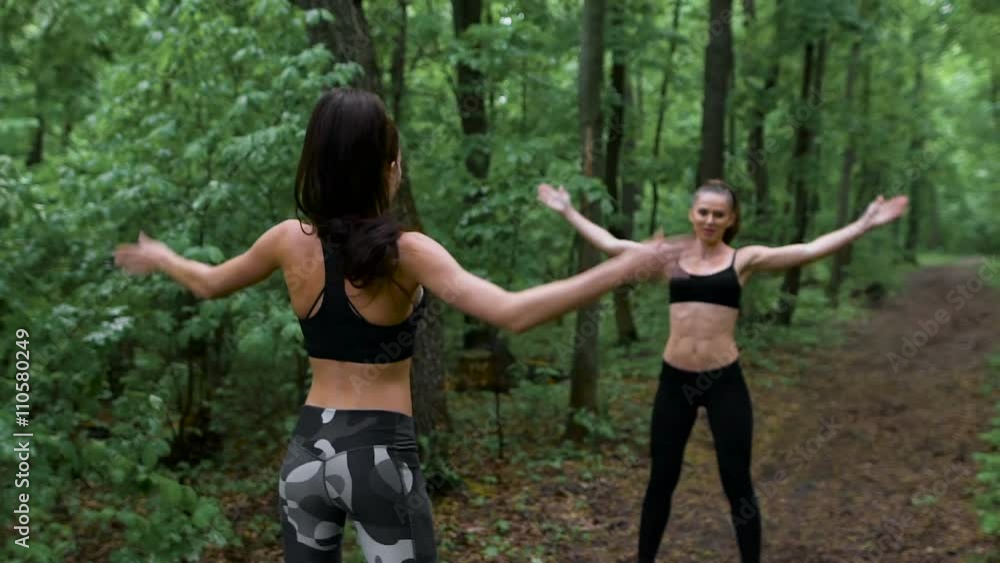 Two sports davushki arranged intensive training in the forest. They perform jumps, their slim attractive figure. Two sports davushki arranged intensive training in the forest. They perform jumps, their slim attractive figure.