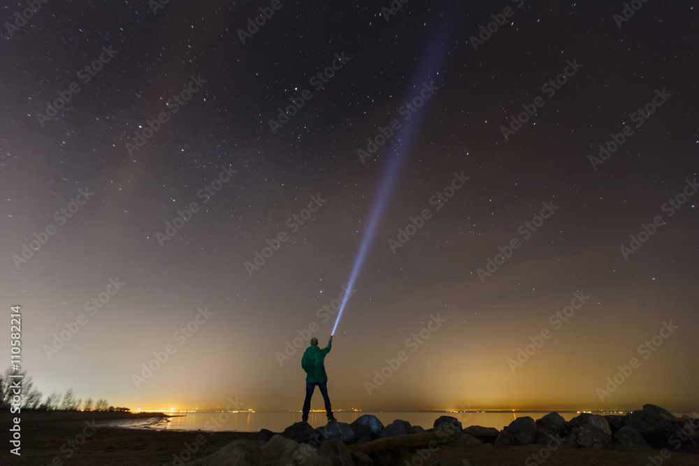 Silhouette of man with flashlight, wide stars and visible Milky way galaxy