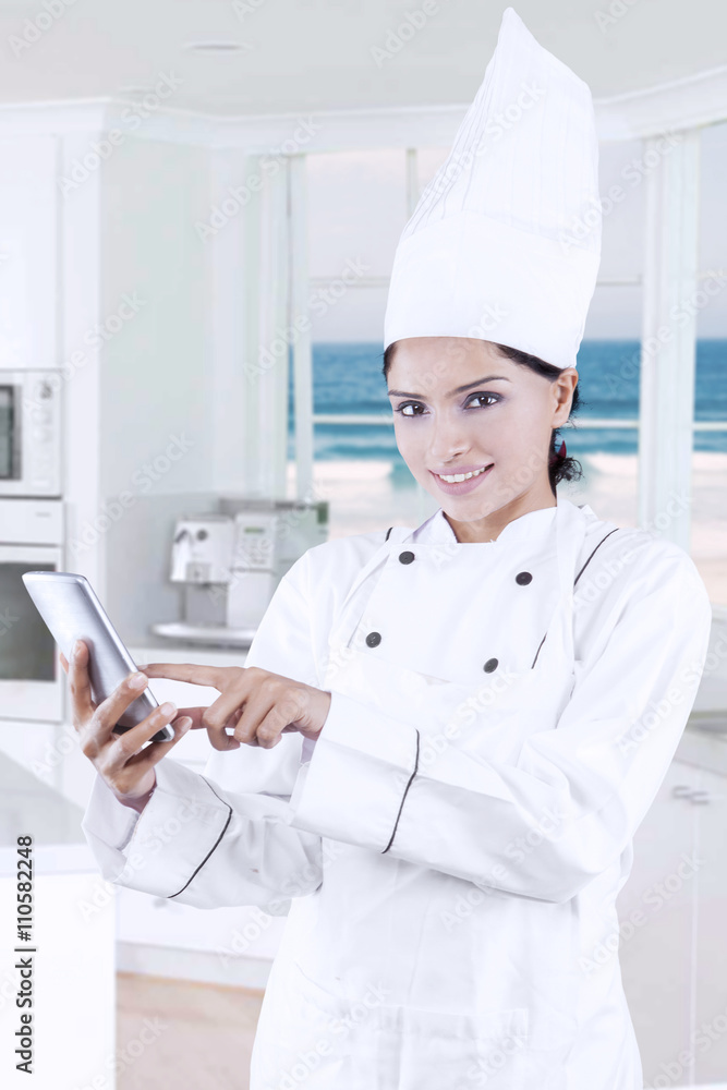 Pretty female chef uses smartphone in kitchen